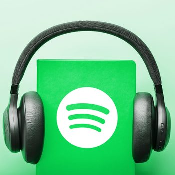 headphones on a green book with spotify logo. green background. audiobook concept