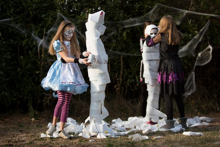 children playing 'wrap the mummy' Halloween game with toilet rolls