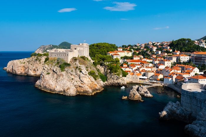 A scenic view of Fort Lovrijenac and the town of Dubrovnik in Croatia. The fortress sits above the coastline and water, and is well known as a filming location for the TV show Game of Thrones.