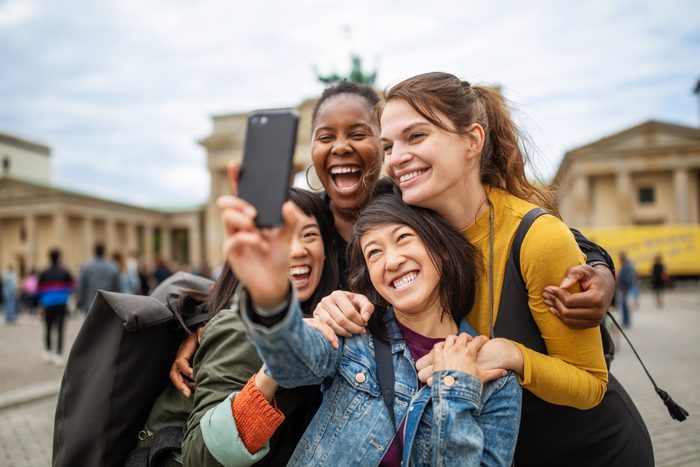 Cheerful friends taking selfie against Brandenburg Gate