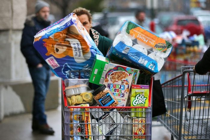 woman pushing an overflowing cart of groceries