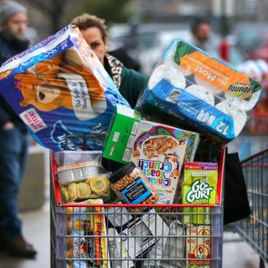 woman pushing an overflowing cart of groceries