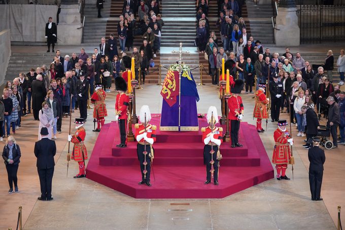 LONDON, ENGLAND - SEPTEMBER 16: Members of the public file past the coffin of Queen Elizabeth II, draped in the Royal Standard with the Imperial State Crown and the Sovereign's orb and sceptre, lying in state on the catafalque in Westminster Hall, at the Palace of Westminster, ahead of her funeral on Monday, on September 16, 2022 in London, England. Members of the public are able to pay respects to Her Majesty Queen Elizabeth II for 23 hours a day until 06:30 on September 19, 2022. Queen Elizabeth II died at Balmoral Castle in Scotland on September 8, 2022, and is succeeded by her eldest son, King Charles III. (Photo by Yui Mok - WPA Pool/Getty Images)