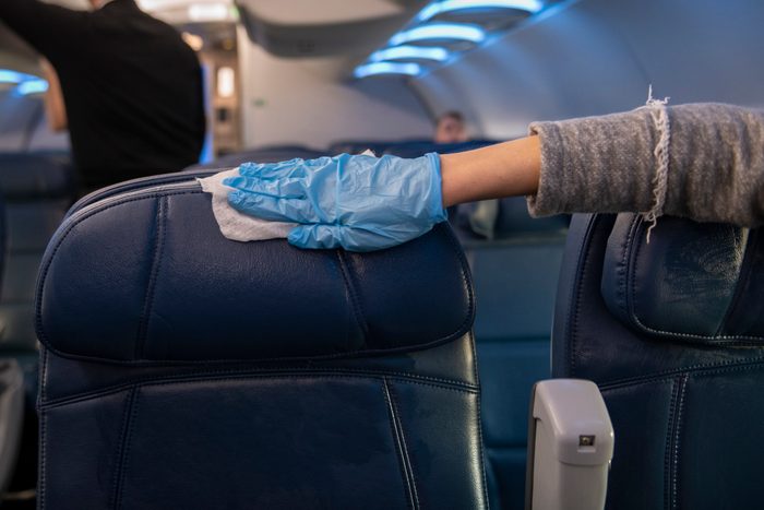 Passenger disinfecting airplane seats after boarding flight
