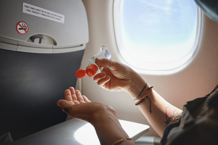 Cropped shot of a woman sanitising her hands in the aeroplane