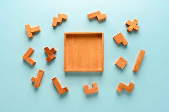 pieces of a wooden iq puzzle scattered around the puzzle frame. blue background