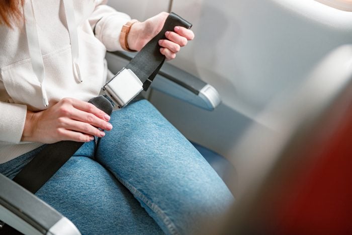 Female traveler hands fastening seatbelt in airplane