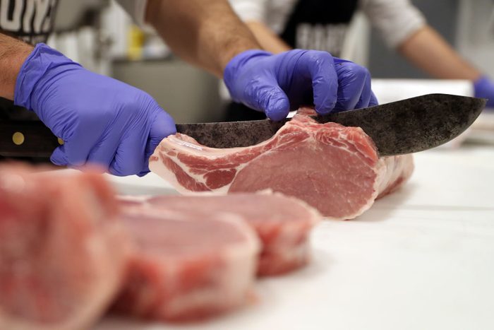 a butcher cuts a piece of meat at the grocery store