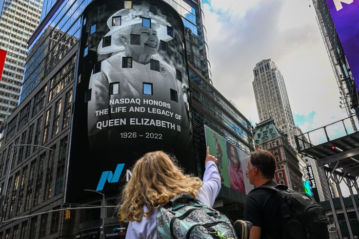 People point to a the Nasdaq billboard displaying a message honoring the life and legacy of Queen Elizabeth II in Times Square on September 08, 2022 in New York, New York.