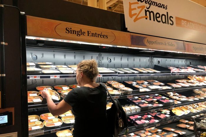 Woman selecting from assorted prepared food entrees at Wegmens high-end grocery store, Boston, Massachusetts