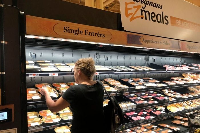Woman selecting from assorted prepared food entrees at Wegmens high-end grocery store, Boston, Massachusetts