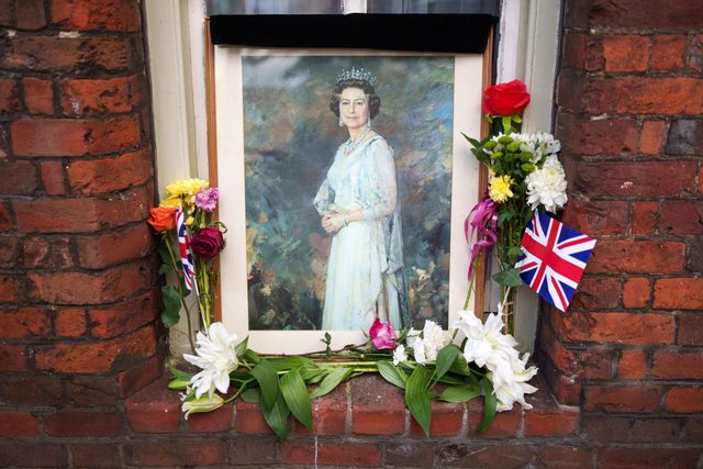 A portrait of Queen Elizabeth II and tributes sit on the window sill of home near Windsor Castle on September 16, 2022 in Windsor, United Kingdom