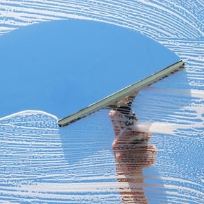 Cleaning and washing a window with a squeegee.