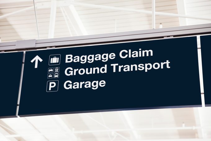 Blue airport sign with baggage claim, ground transportation, and garage information and a Directional arrow