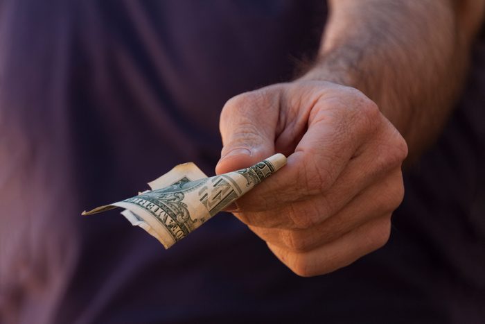 Man hand holding a folded dollar bill.