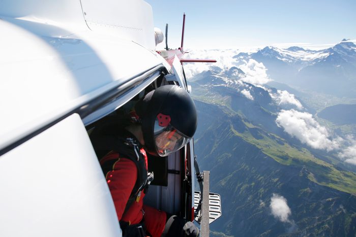 Female sky diver in helicopter checking for exit over mountain, Interlaken, Berne, Switzerland