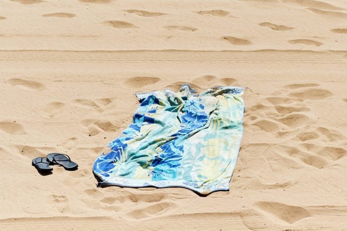 Rumpled beach towel and lonely flip flops in the sand