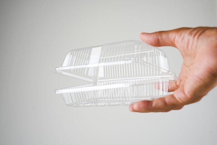 cropped hand holding plastic food container