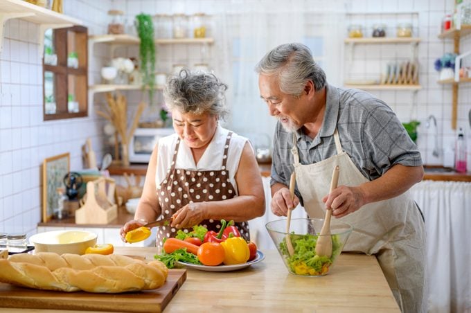Asian Elderly Happy Couple Making Healthy Food In The Kitchen At Home. Elderly Spending Time Together Concept.