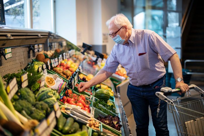 Senior man with face mask buying vegetables in grocery store