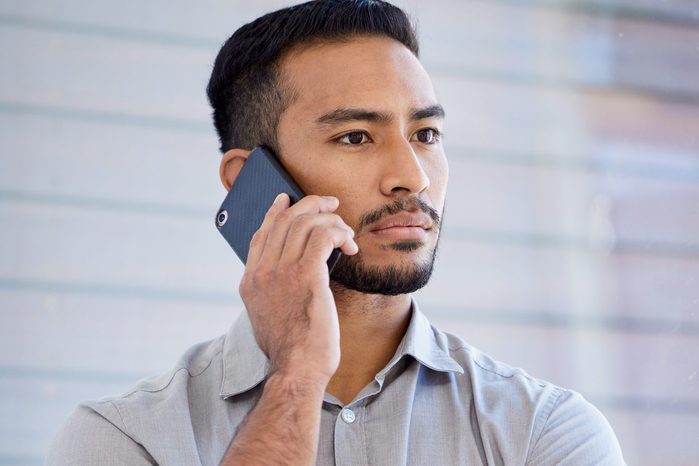 young man holding a phone to his ear with a serious expression on his face