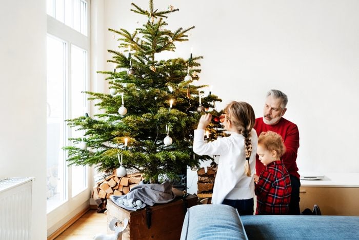 Grandpa Spending Time With Grandchildren Decorating Christmas Tree