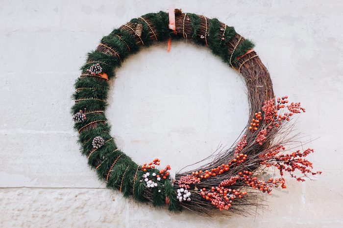 Large Christmas wreath with fir branches, toys and decorations on the wall of the house on the street.