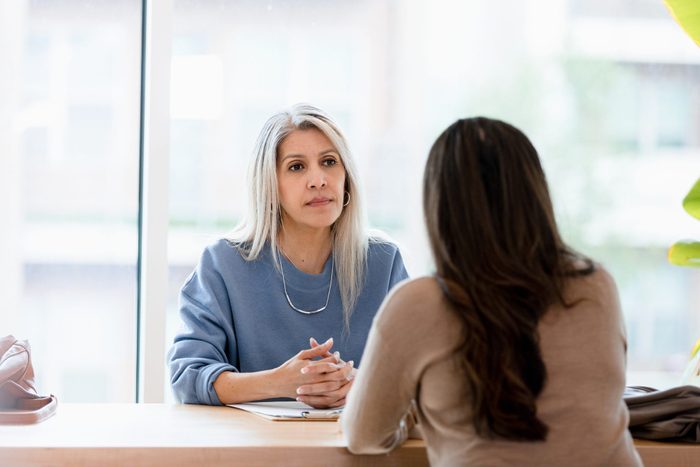 Serious businesswoman listens to unrecognizable female client