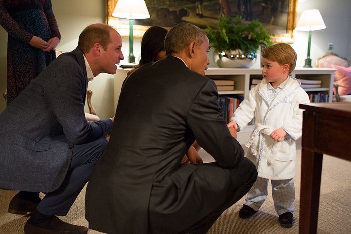 in 2016, Obama bends down to meet Prince George who is wearing a white bathrobe