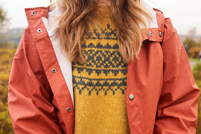 close up of a woman wearing a yellow wool sweater and a winter coat over top