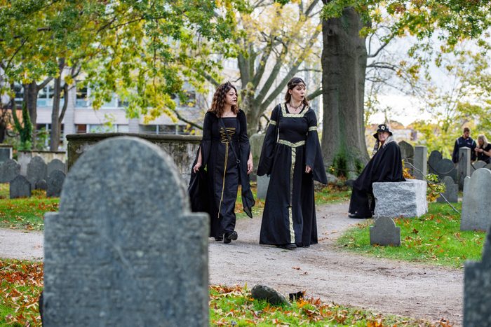 people dressed up in halloween costumes walking through a cemetery in Salem, MA