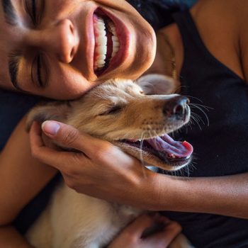 Happy Woman Cuddling With Dog