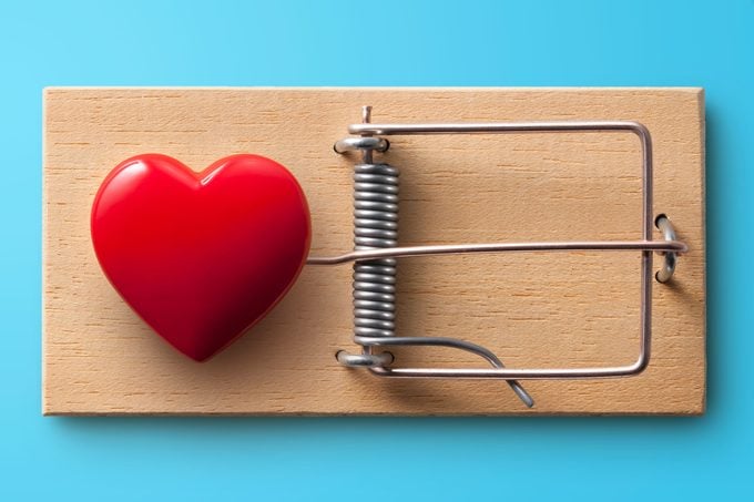 heart set as bait in a mouse trap on blue background