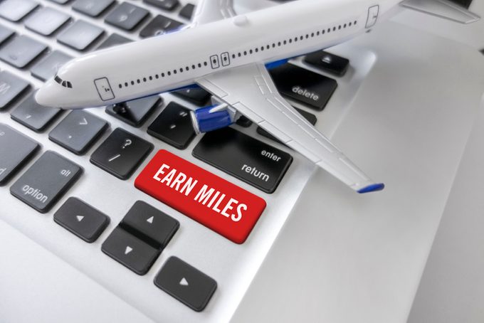 Miniature airplane sits on laptop with an "Earn Miles" button