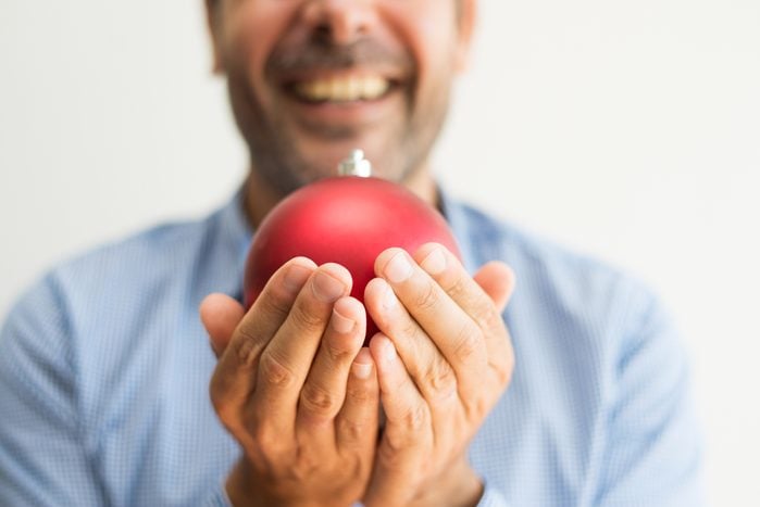 Excited man holding a large red christmas ornament