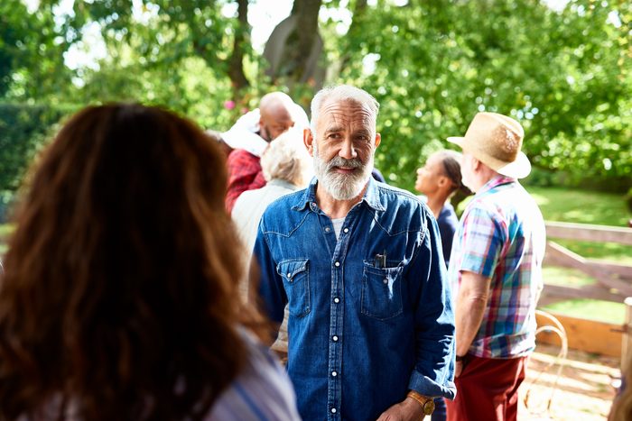 Mature man chatting to guest at garden party