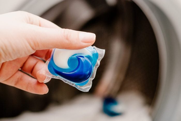 hand holding a laundry pod before placing it in the washing machine