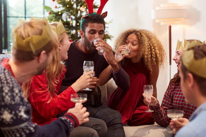 Group Of Friends Celebrating With Champagne After Enjoying Christmas Dinner At Home