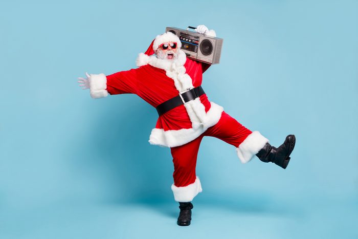 santa having a good time listening to music, holding boombox on shoulder; blue background