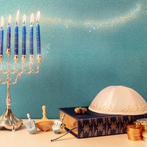 hanukkah still life with traditional chandelier menorah, wooden spinning top toy (dreidel) and other religious attributes