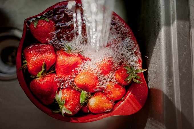 Bowl of Strawberries Under Running Water in a Kitchen Sink