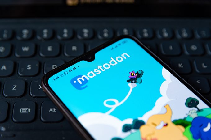 Mastodon app homepage on a mobile phone rests on keyboard