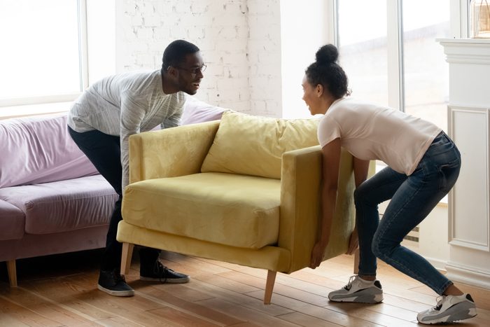 African couple moving a chair in a living room