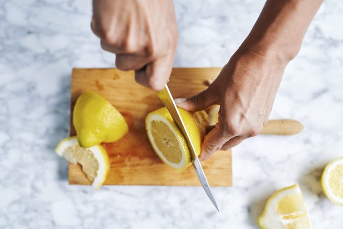 Hands of woman cutting lemons on cutting board