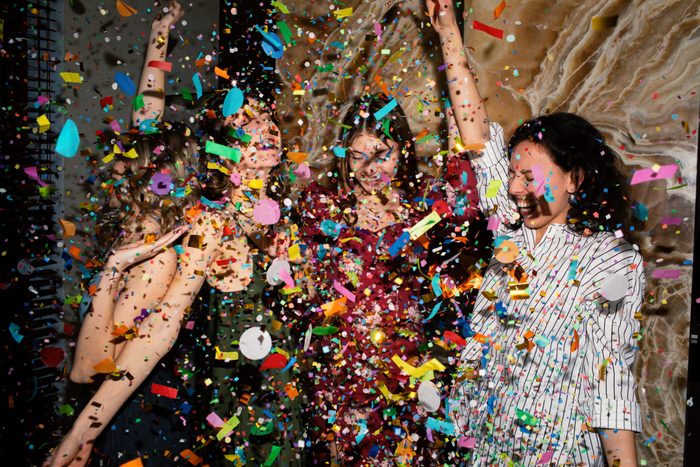 Group of friends having fun with confetti at home.