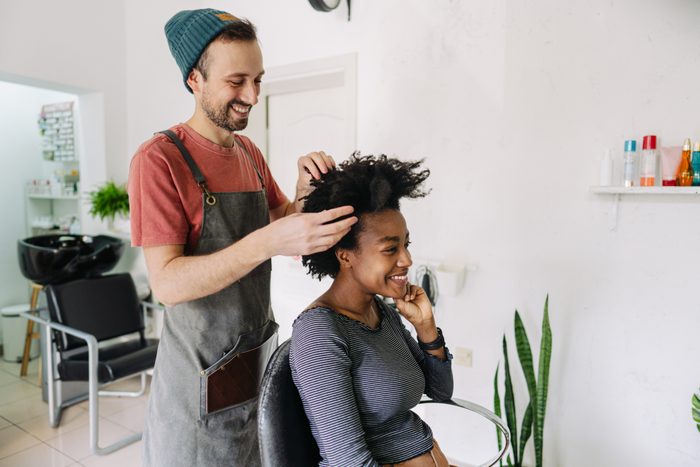 Photo of a young smiling hairdresser, serving a customer with an Afro hair