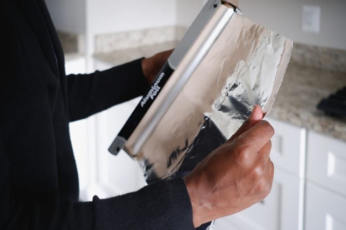 Woman Removes Aluminum Foil From Container