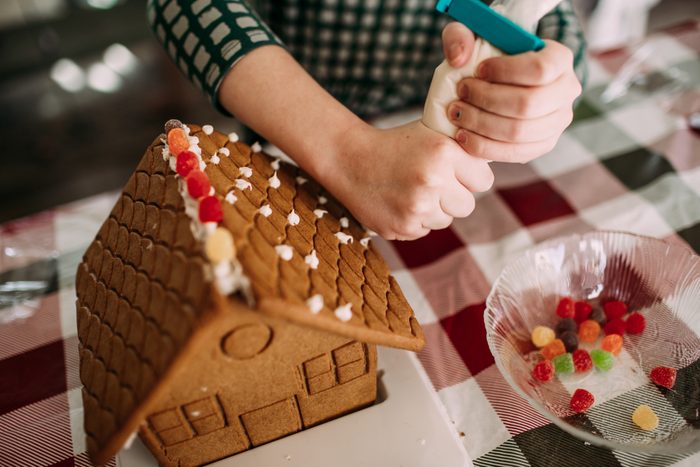 Young girl decorating a ginger bread house at a table