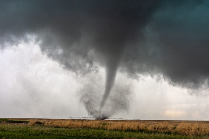 A tornado spins in a field beneath a supercell thunderstorm during a severe weather event in Selden, Kansas.