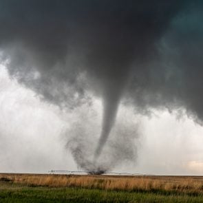 A tornado spins in a field beneath a supercell thunderstorm during a severe weather event in Selden, Kansas.